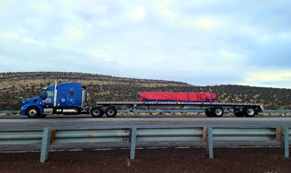 An ATS flatbed truck hauling a tarped load