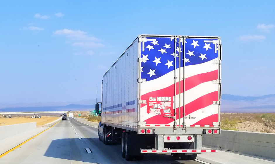 A semi truck with an American flag painted on the trailer doors