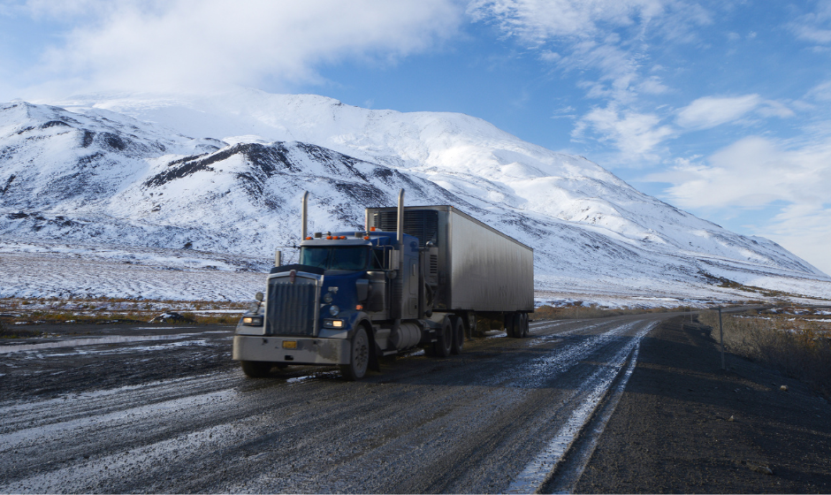 A semi with dry van trailer travels an icy Alaskan road