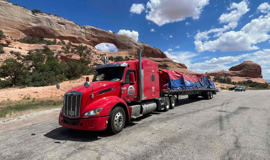 A semi truck with flatbed trailer and tarped freight