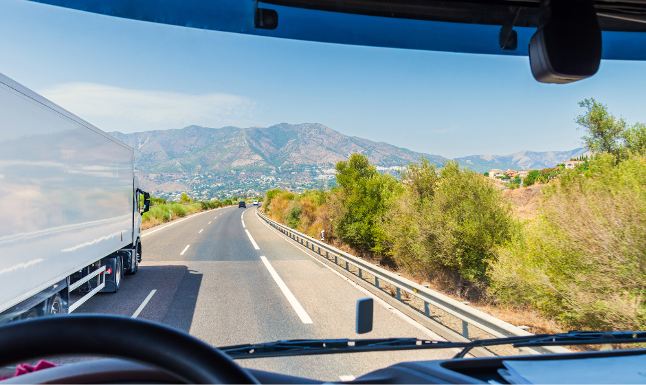 View from behind the wheel of a semi-truck traveling a highway in a mountainous region