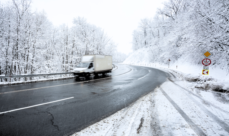 A refrigerated truck travels on a road in winter