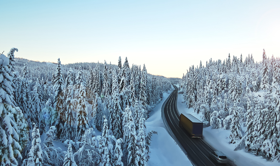 A truck and car travel on an Alaskan highway in winter