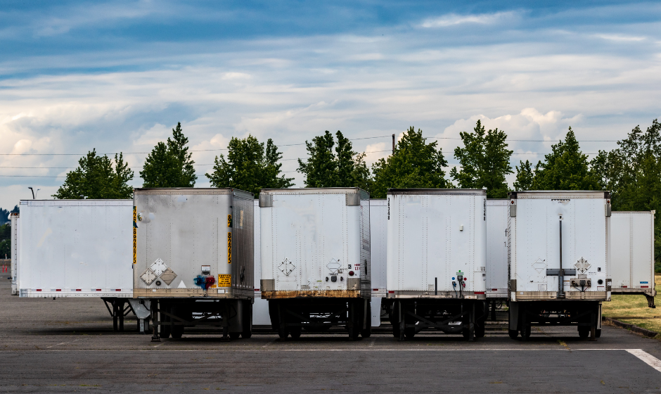 Empty dry van and reefer trailers in a parking lot.