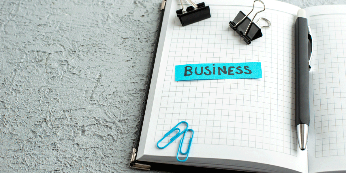 Grid-line notebook with paperclips and the word business written in blue.