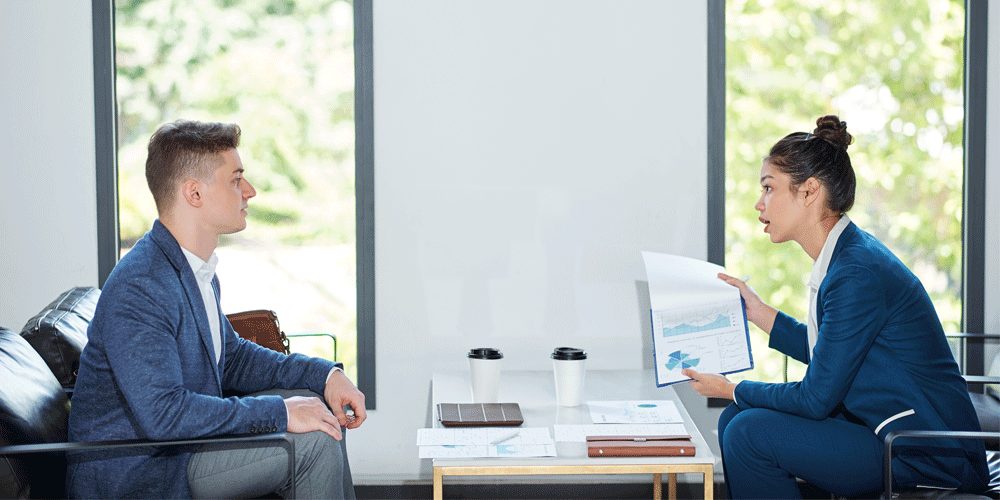 Two people sitting opposite each other reviewing documents.