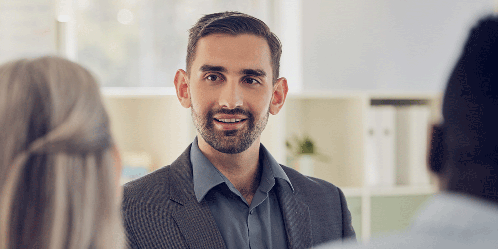 Businessman speaking to two coworkers.