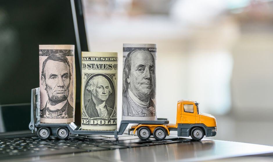 A toy flatbed carries several rolls of U.S. currency